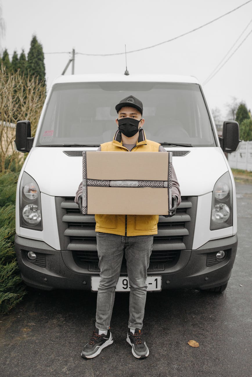 man with a box standing beside a delivery van